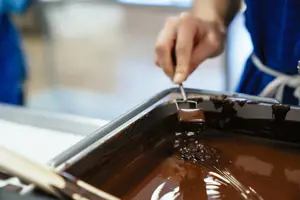 Chocolate being stirred in a tin in a factory.